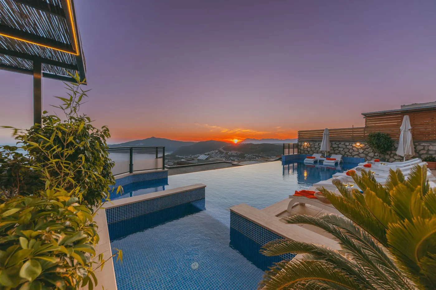 Infinity pool edge at a resort facing an orange sunset
