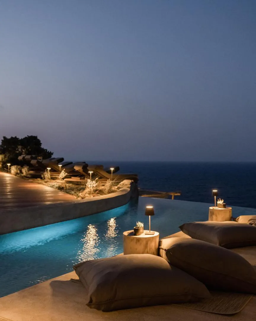 Infinity pool at dusk at Acro Suites, lit terrace and sea view