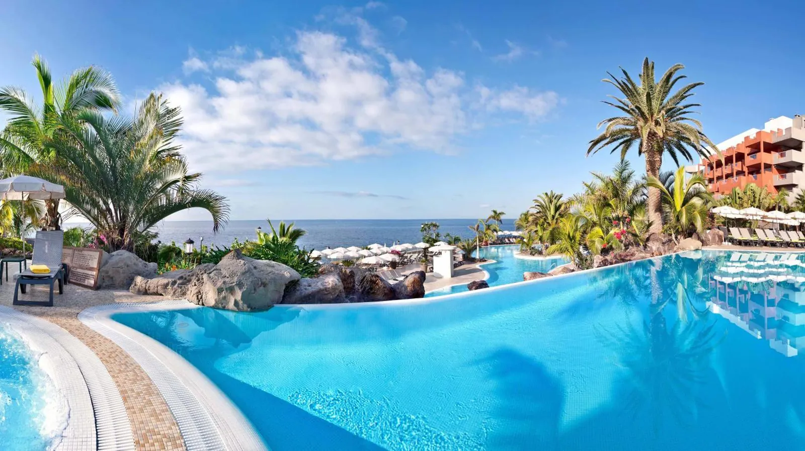 Large blue pool among palms beside the sea