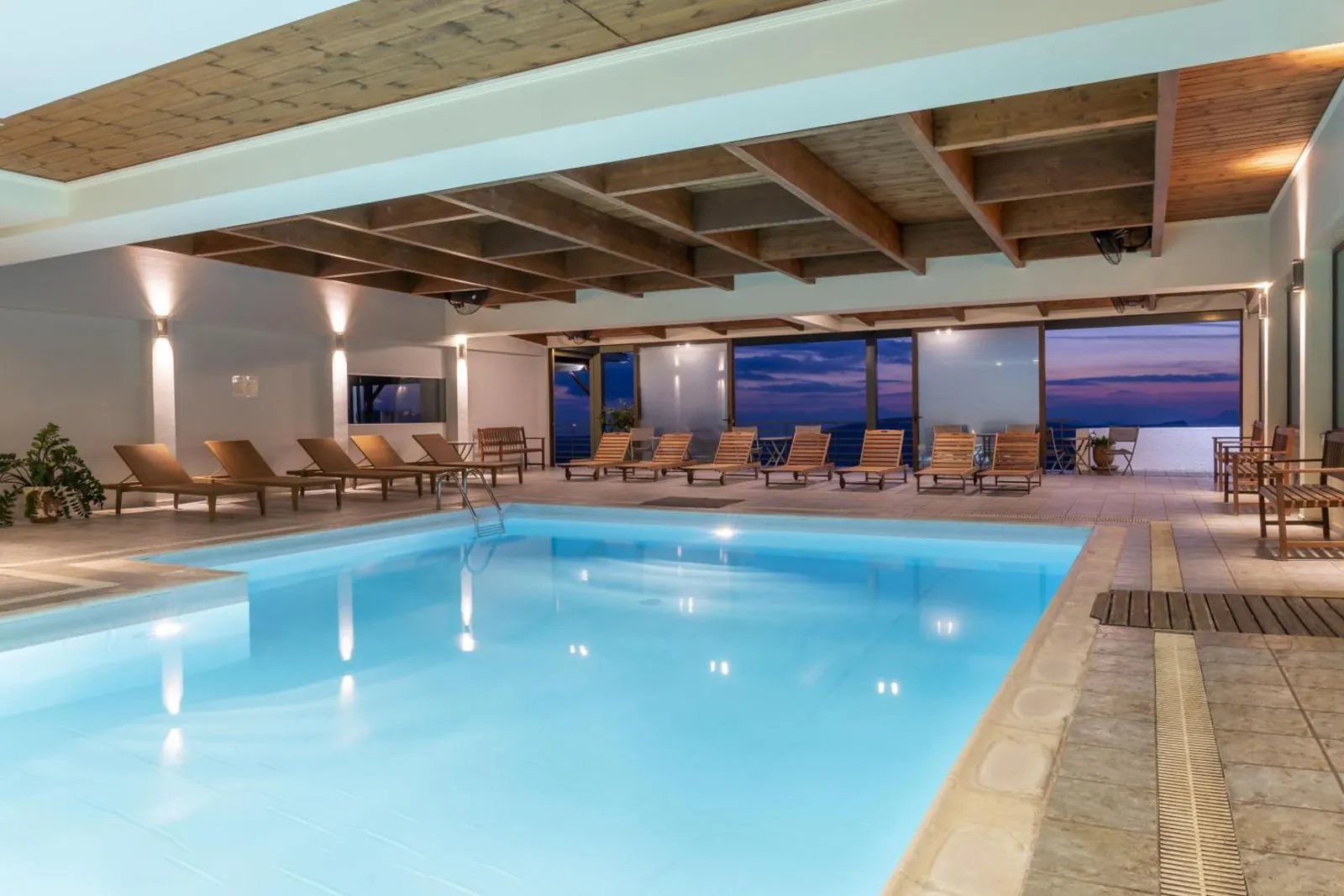 Long indoor pool with loungers lined up along the window wall