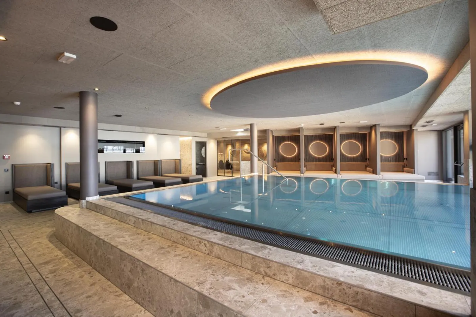 Indoor pool with a stone surround and a round ceiling light at Aparthotel Familiaris