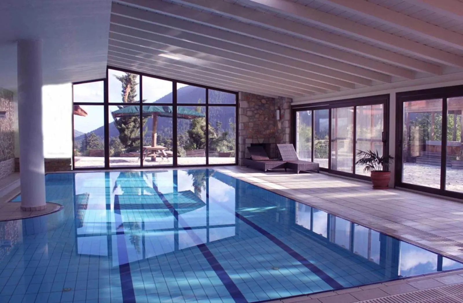 Indoor pool framed by tall glass walls looking onto the mountainside