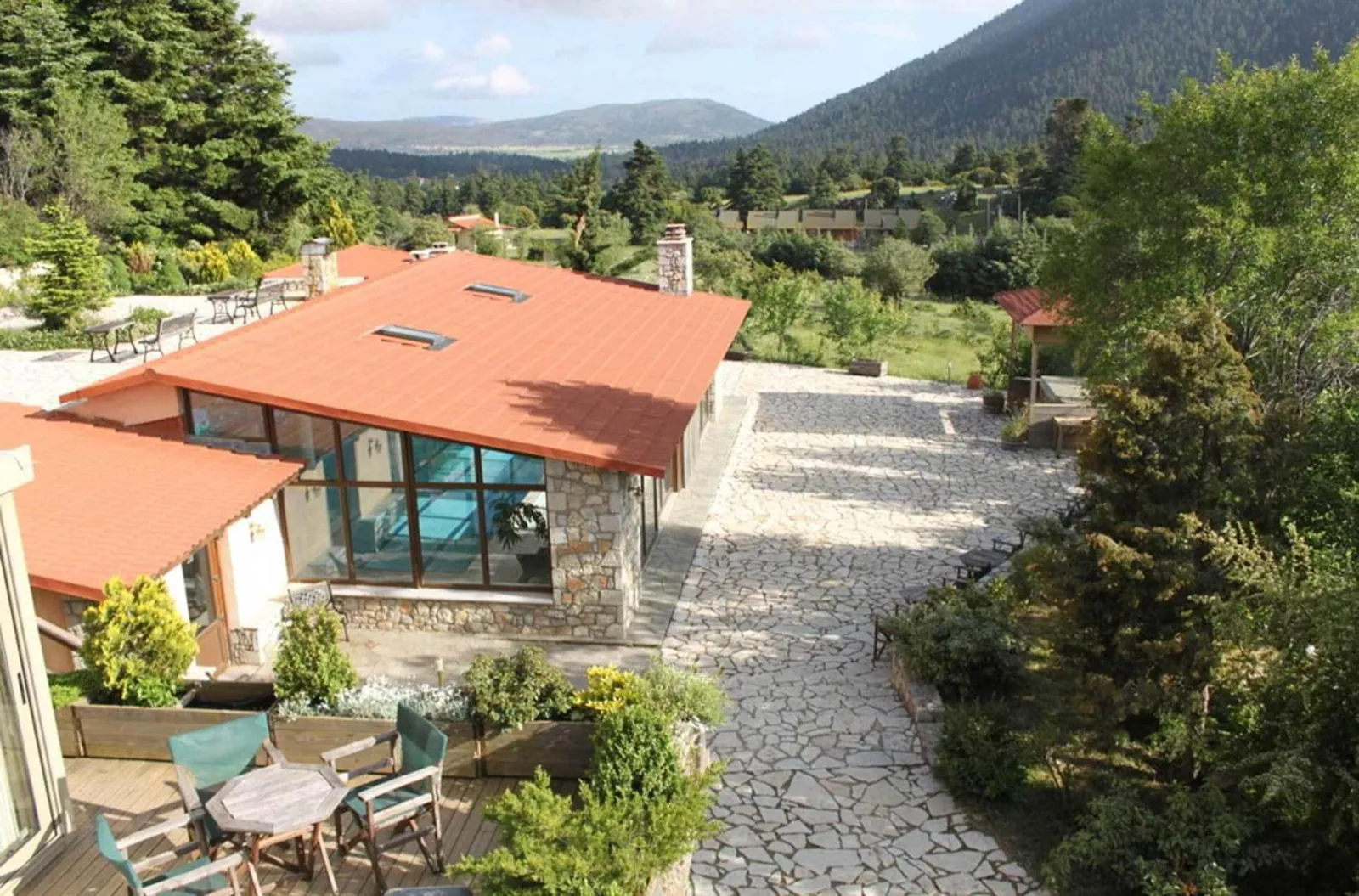 Glass-fronted pool building with a terracotta roof seen from above