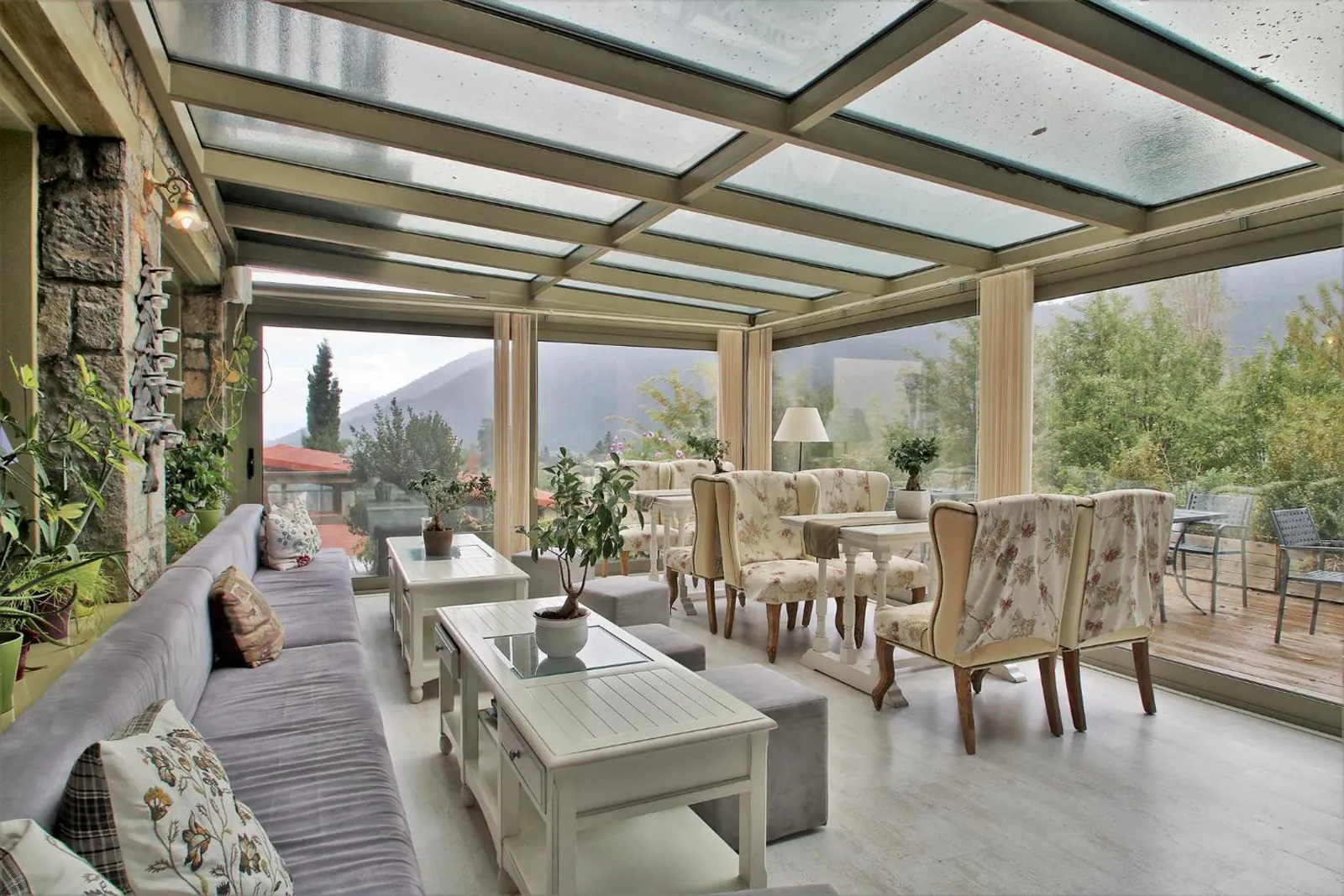 Glass-roofed lounge with wicker seating and mountain views