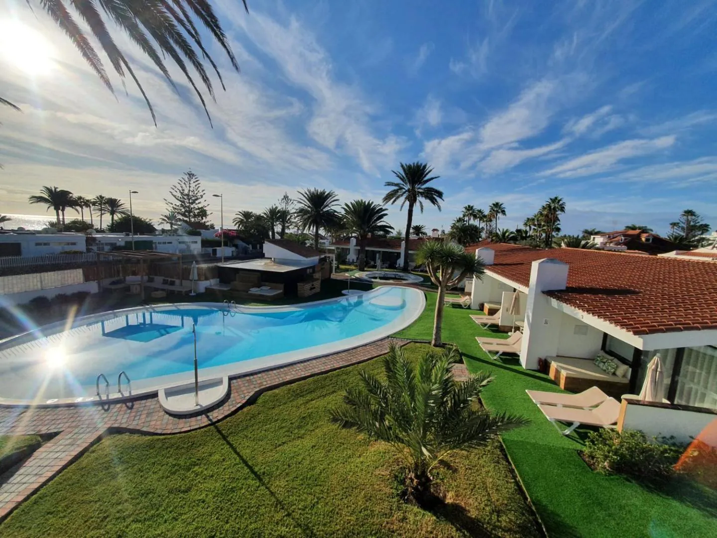 Pool and white bungalows with red-tiled roofs seen from above