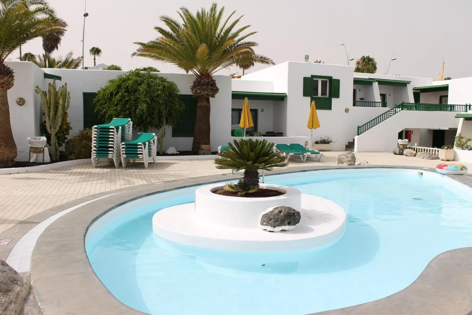 Smaller pool with a planted island in the middle, in front of the bungalows