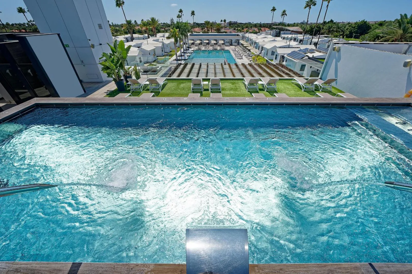 Jet pool with bubbling water, the main pool and bungalows behind