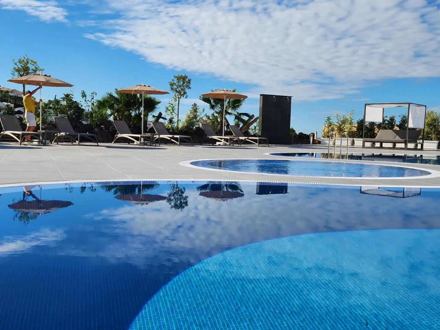 Pool deck with parasols, palms and the sea beyond
