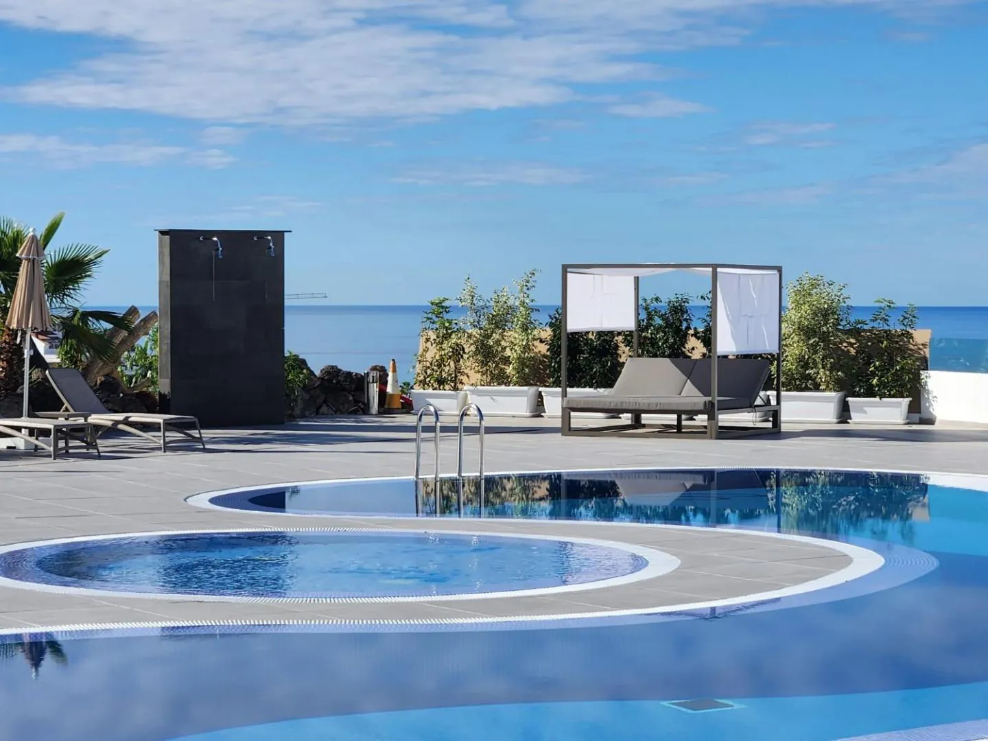 Pool with shaded daybeds and a sea view