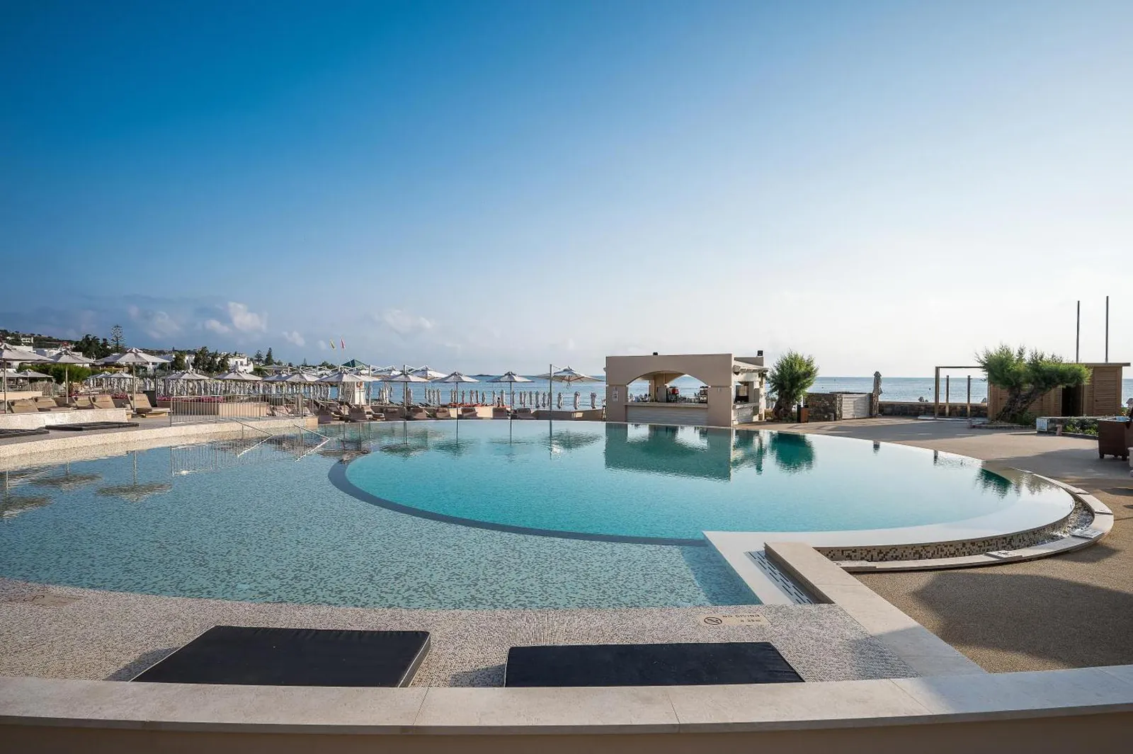 Round pool edged with sun mats, looking out to sea