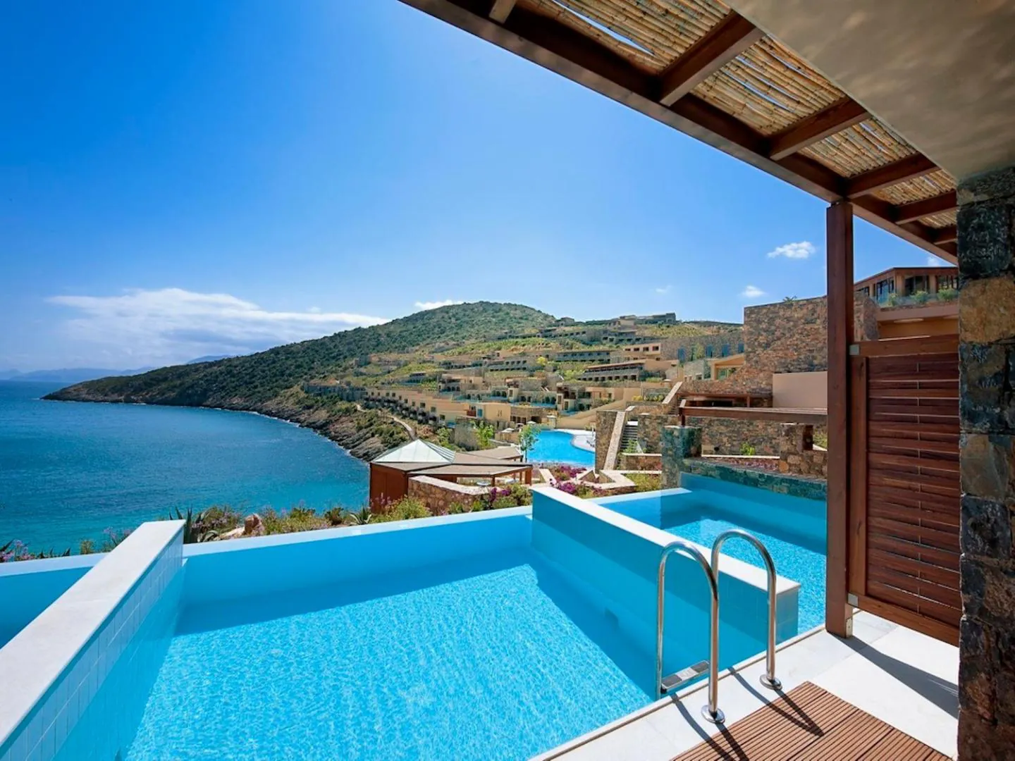 Private pool on a stone terrace with the green hills of the bay beyond