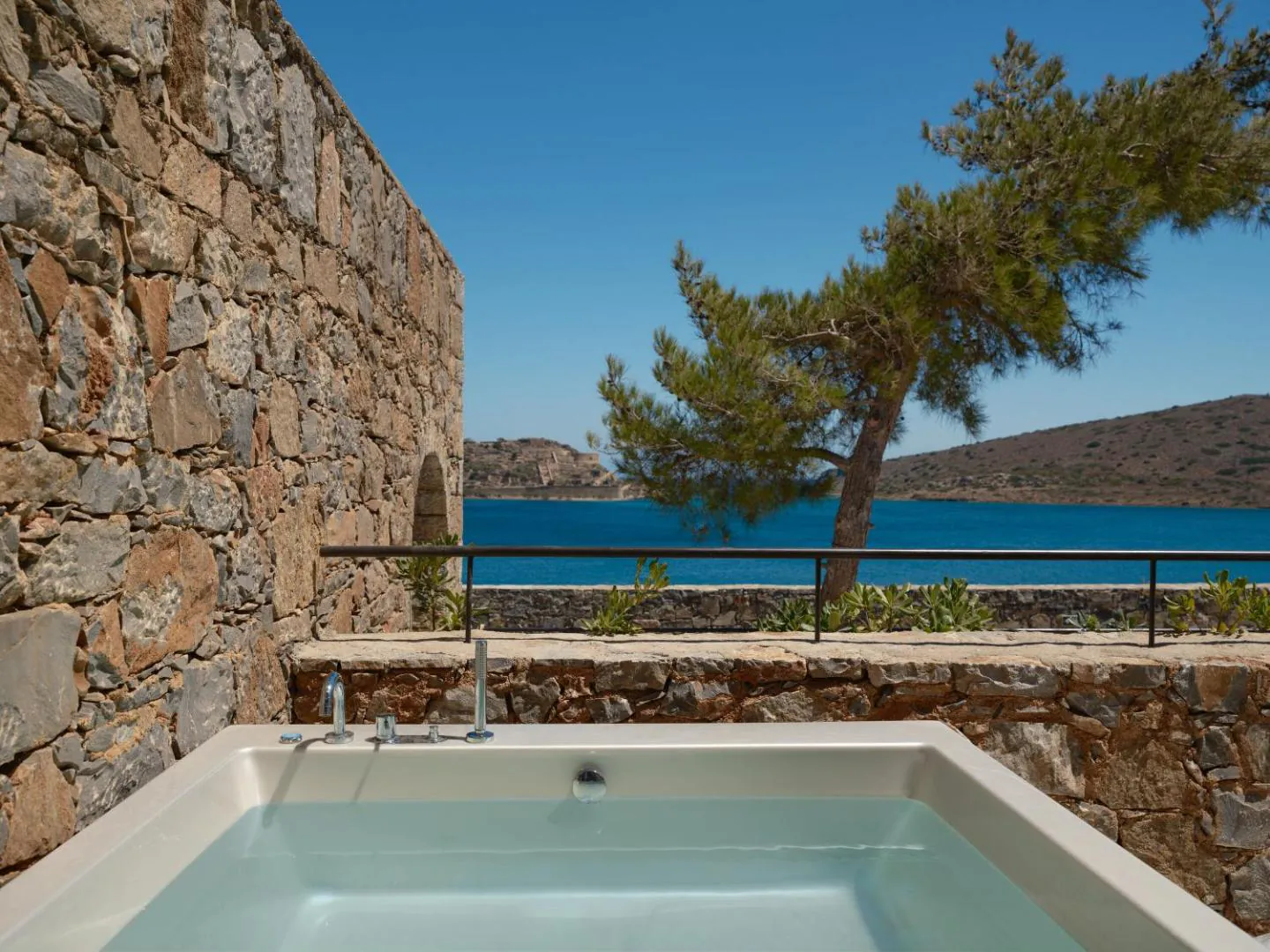 Outdoor hot tub on a stone-walled terrace above the sea