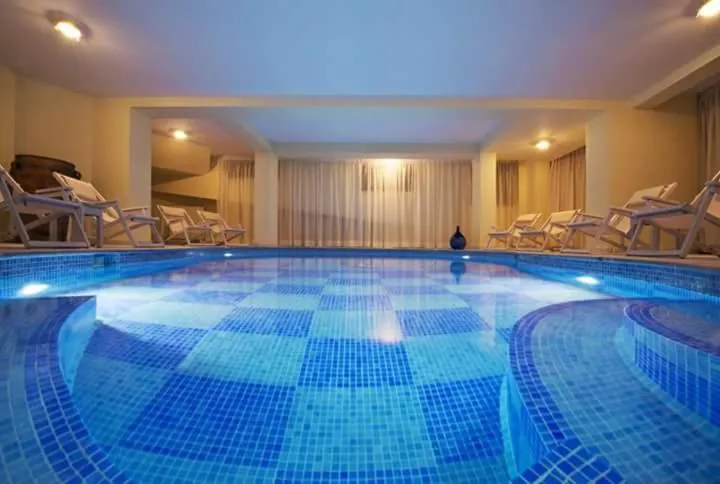 Indoor pool with a blue tiled floor and loungers along the far wall at Ellinon Thea Arachova
