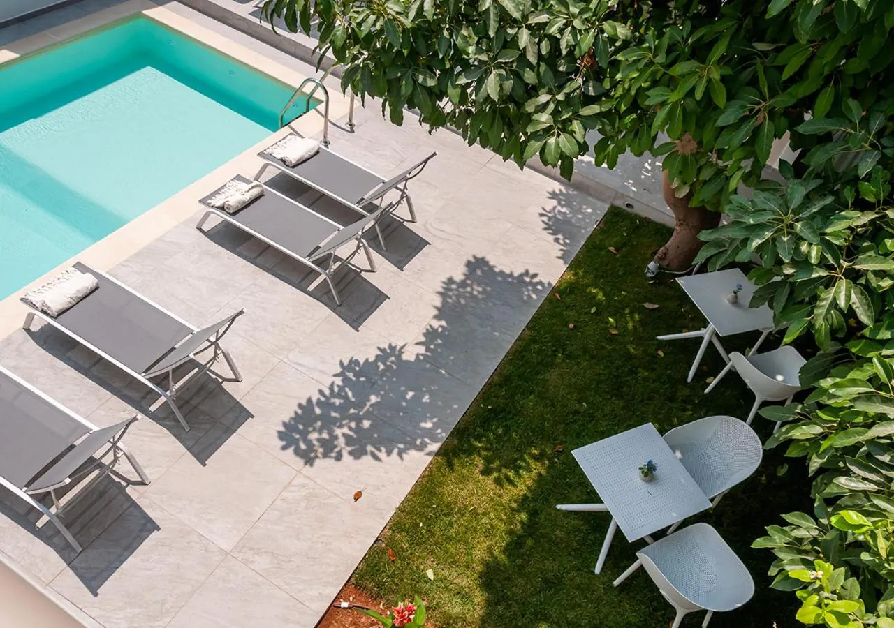 Pool and row of loungers seen from above, shaded by a large tree