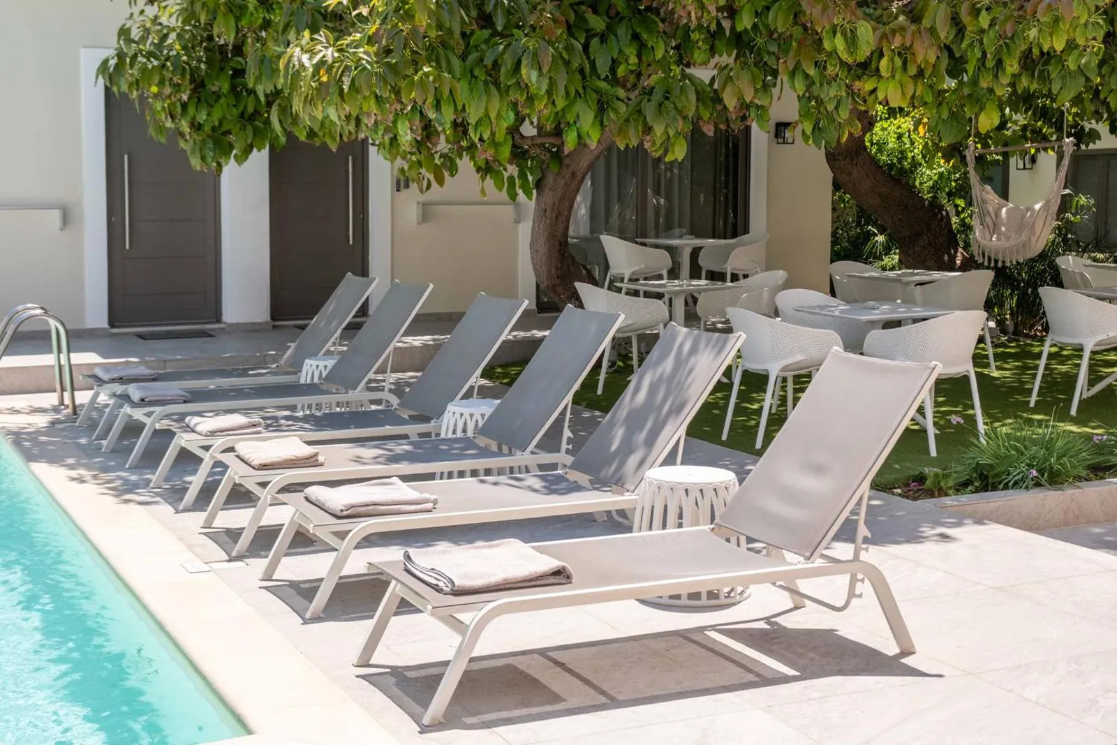 Sun loungers beside the pool under the garden tree