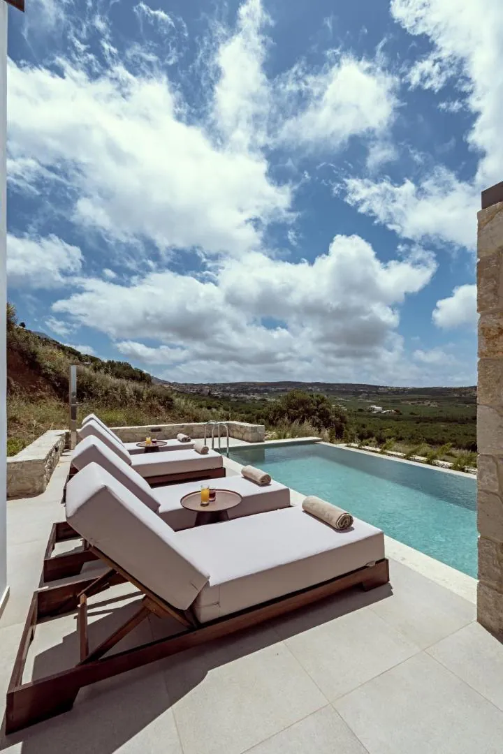 Loungers at the pool's edge facing the hillside and the coast