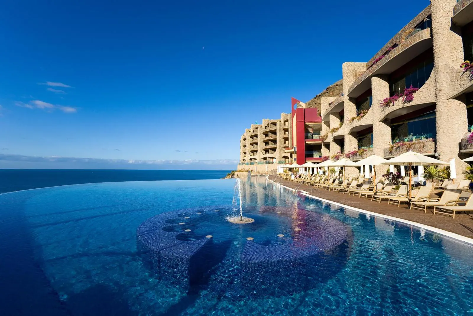 Infinity pool with a round section, the hotel terraces built into the cliff
