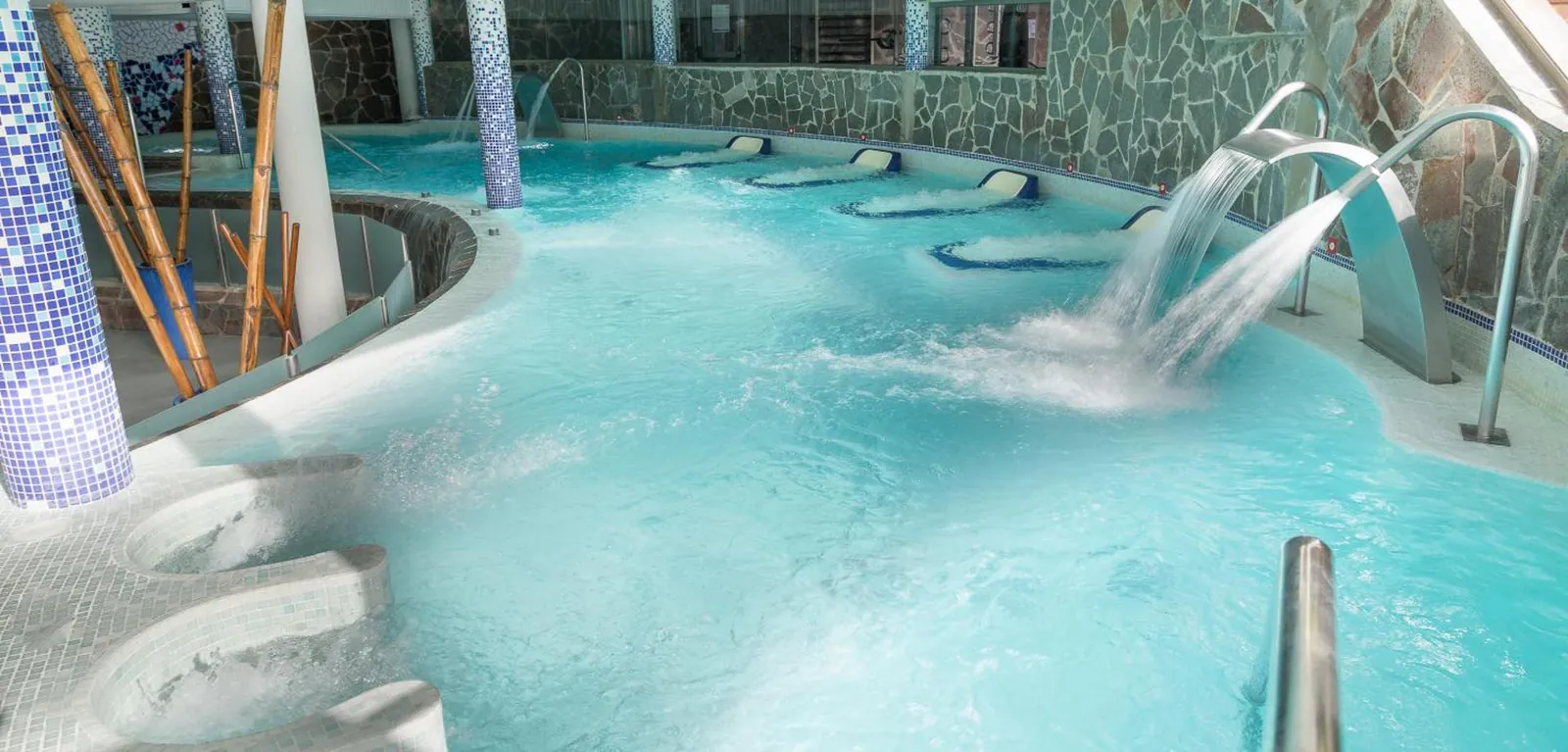 Indoor spa pool with swan-neck jets under blue lighting