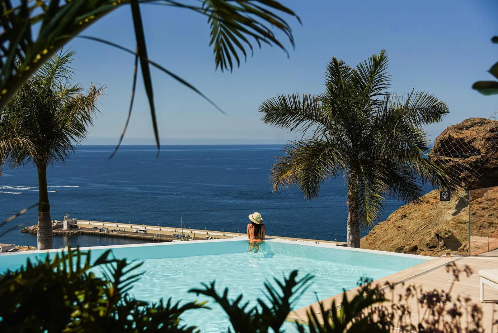 Infinity pool edge at Grand Horizon meeting the Atlantic, palms framing the view