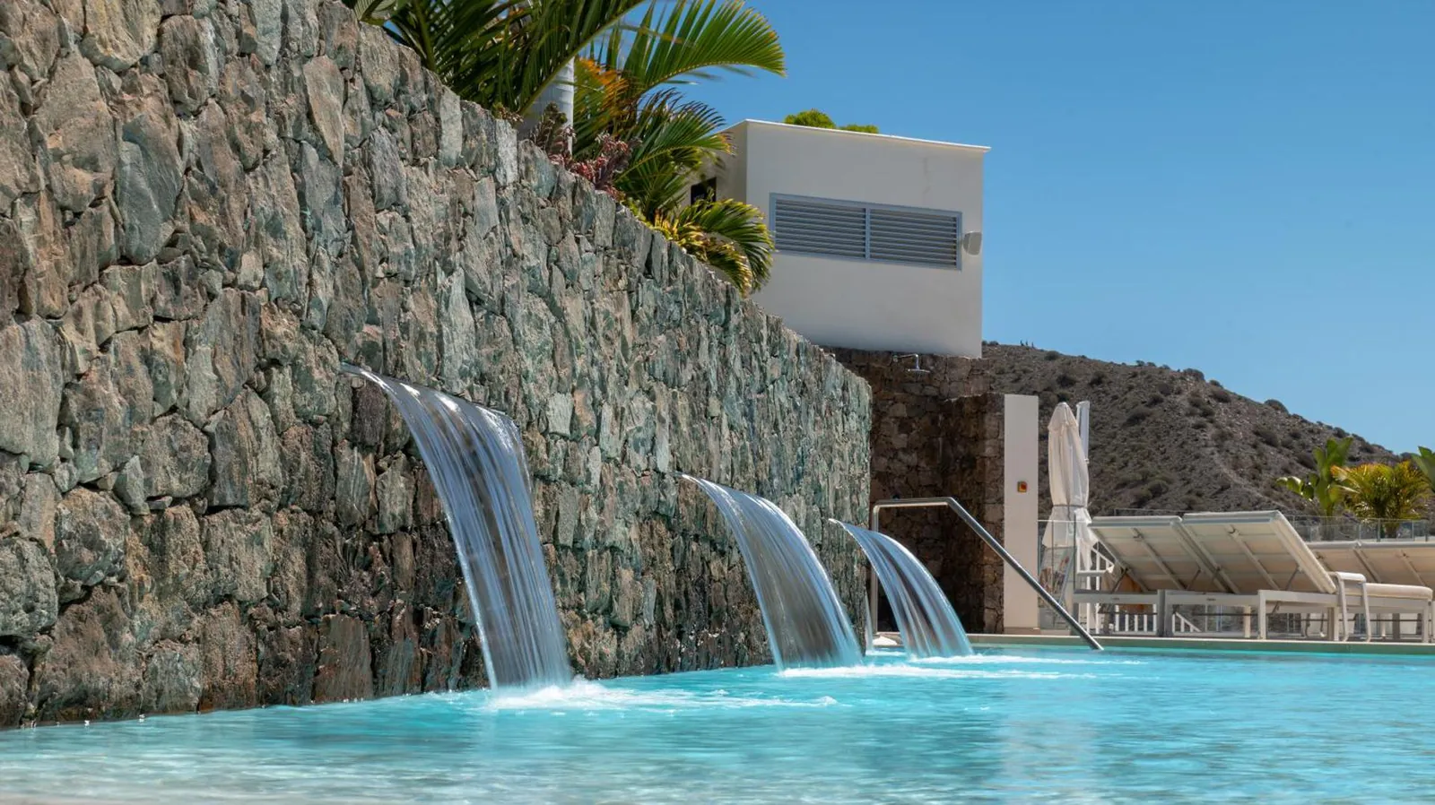 Water spouts pouring from a stone wall into the heated pool
