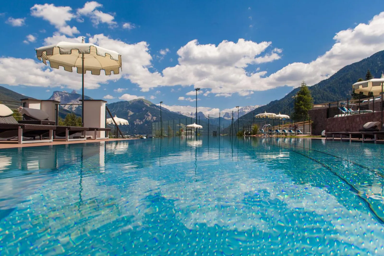 Infinity pool at Hotel Albion with parasols and the Val Gardena mountains beyond