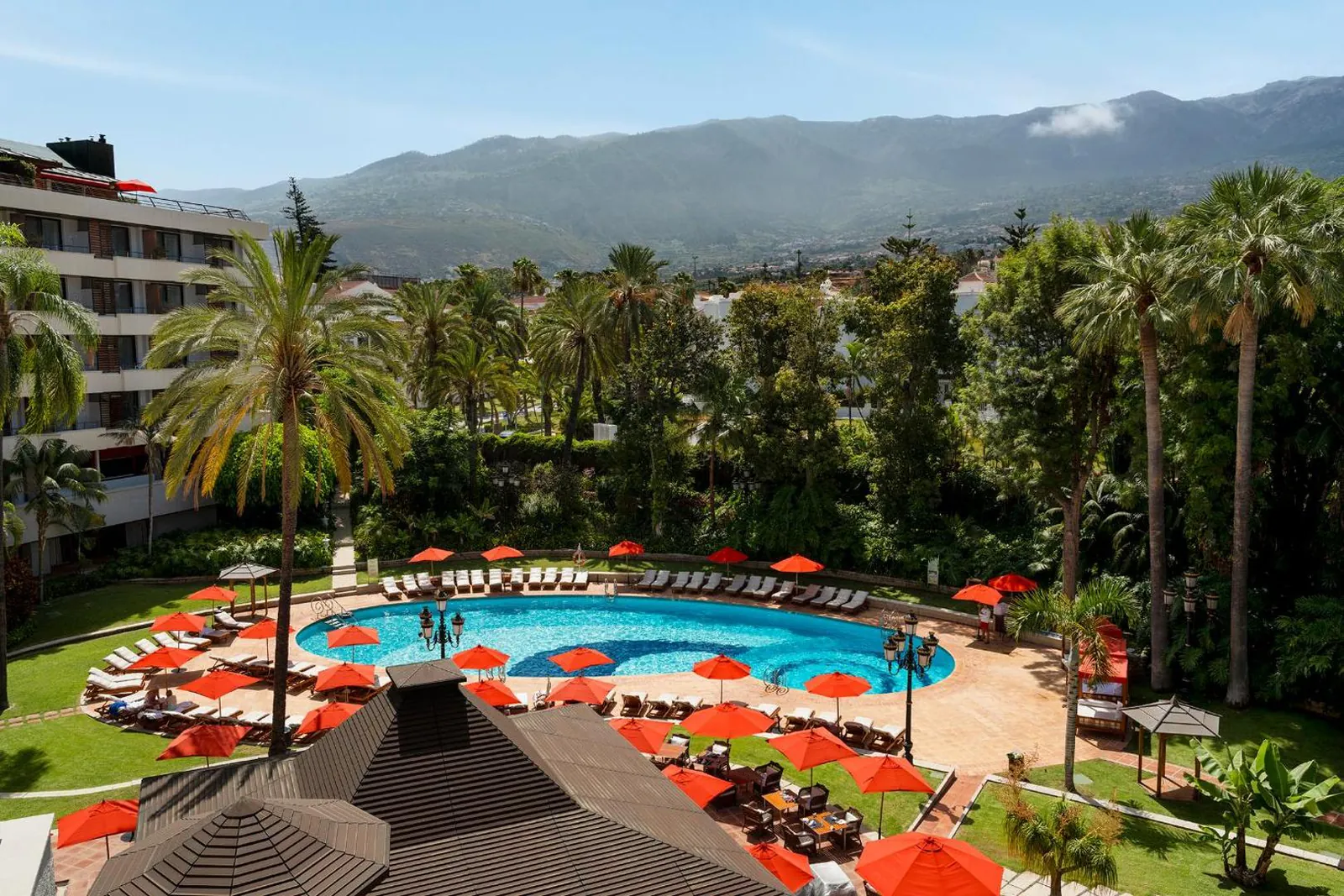Pool terrace with red parasols and mountains behind