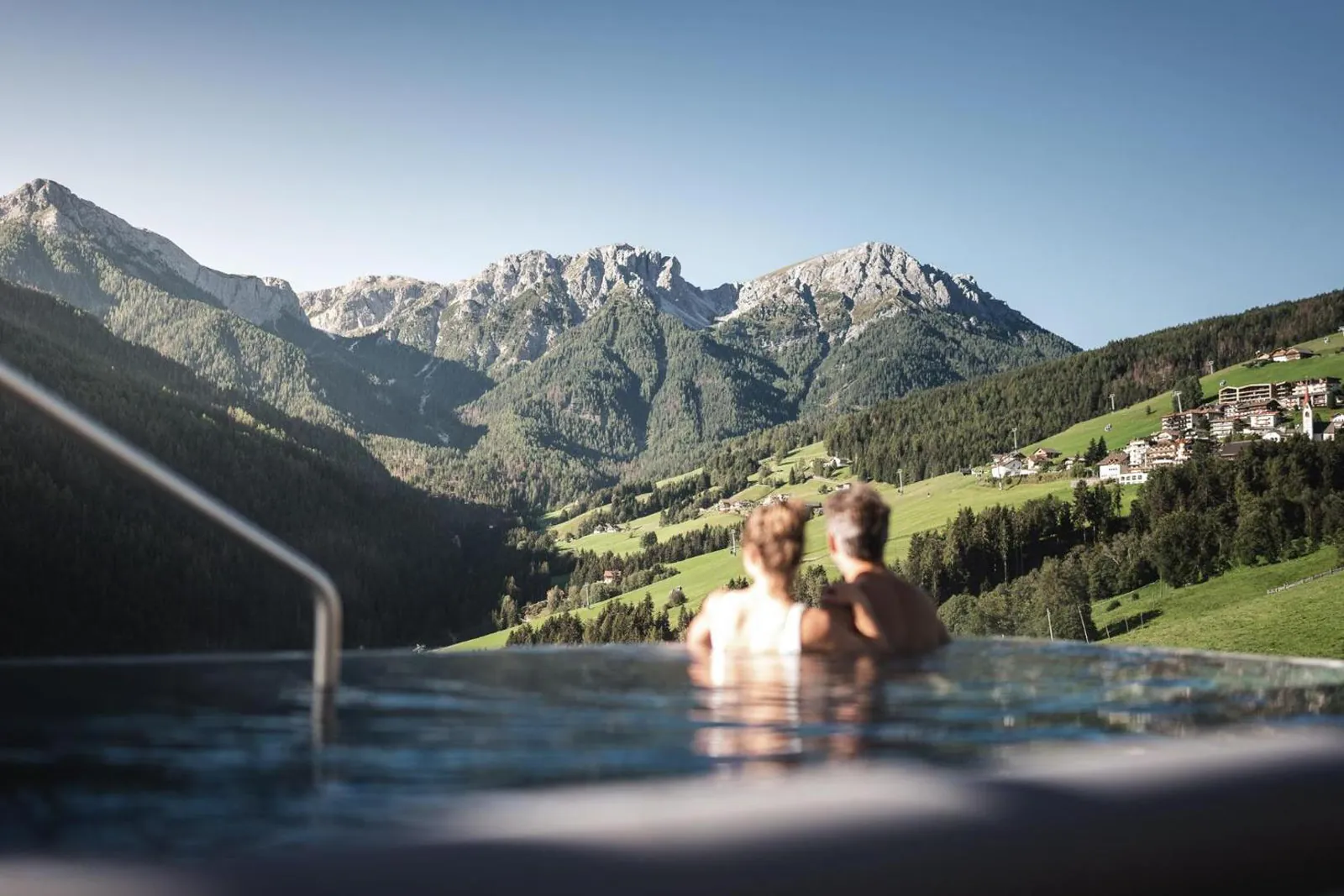 Swimmers in the Sky Pool with the Dolomite peaks and valley meadows beyond