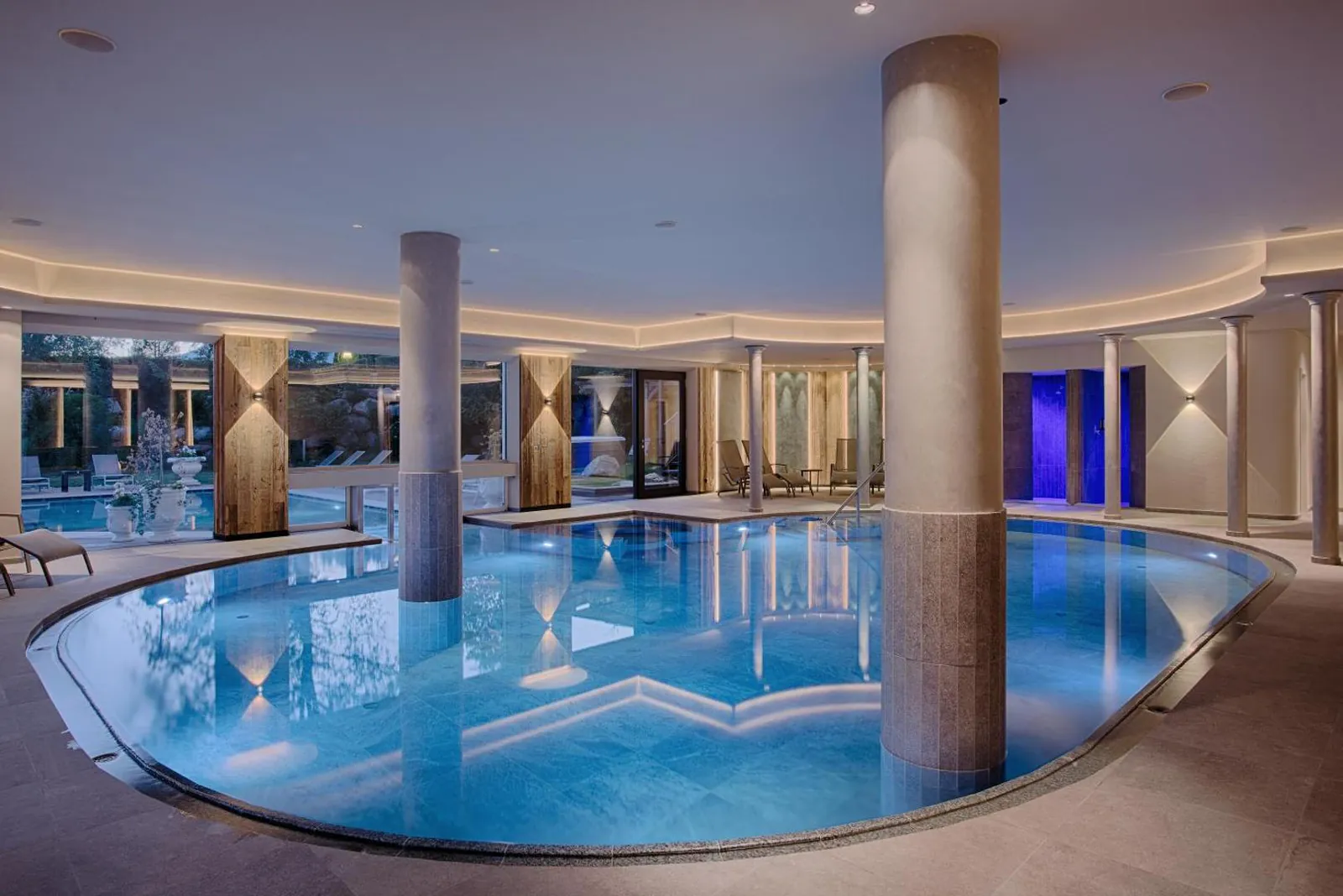 Curved indoor pool with stone columns lit in the evening