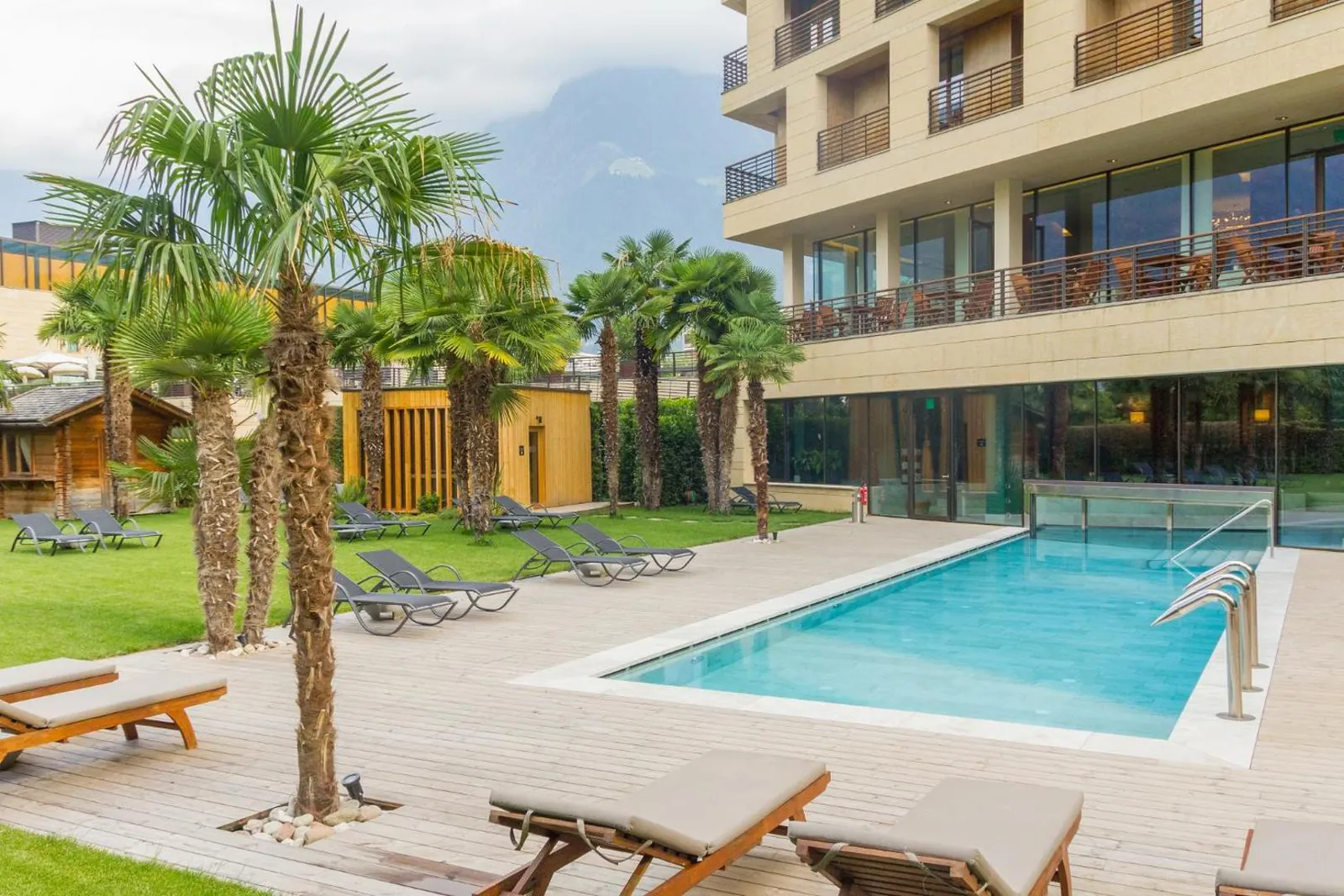 Garden pool with palm trees and sun loungers beside the hotel