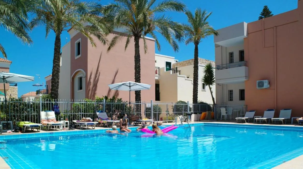 Pool with loungers and umbrellas between the apartment buildings in Platanias