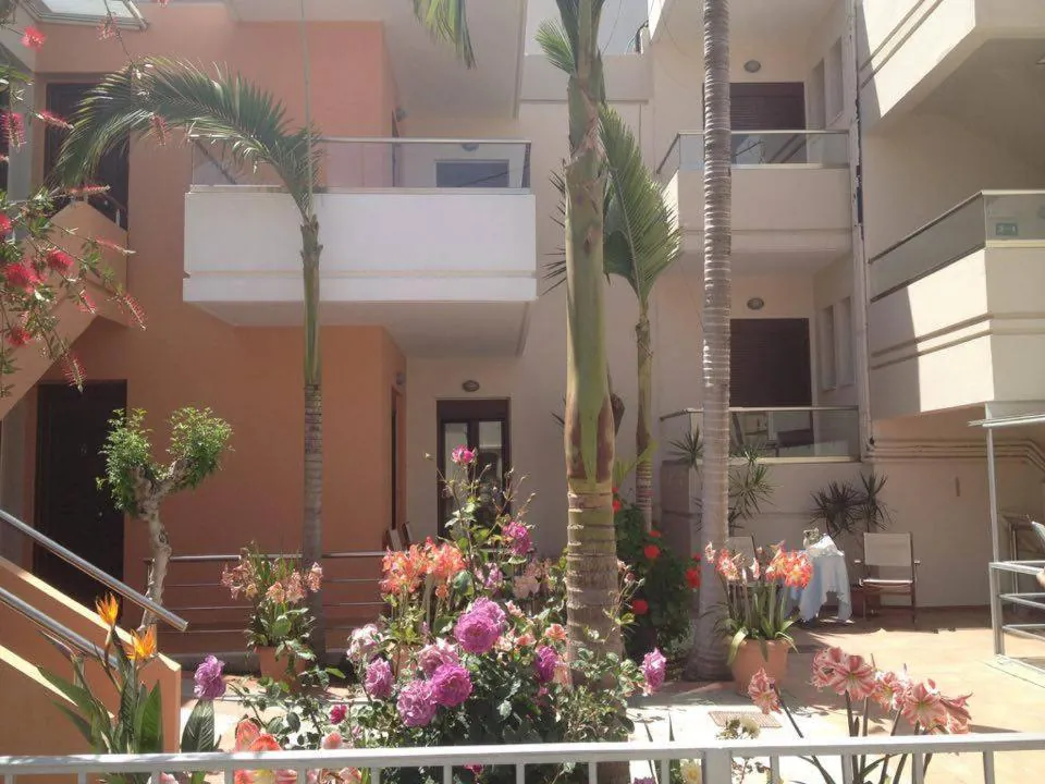 Courtyard with flower beds and palms between the pink and white buildings