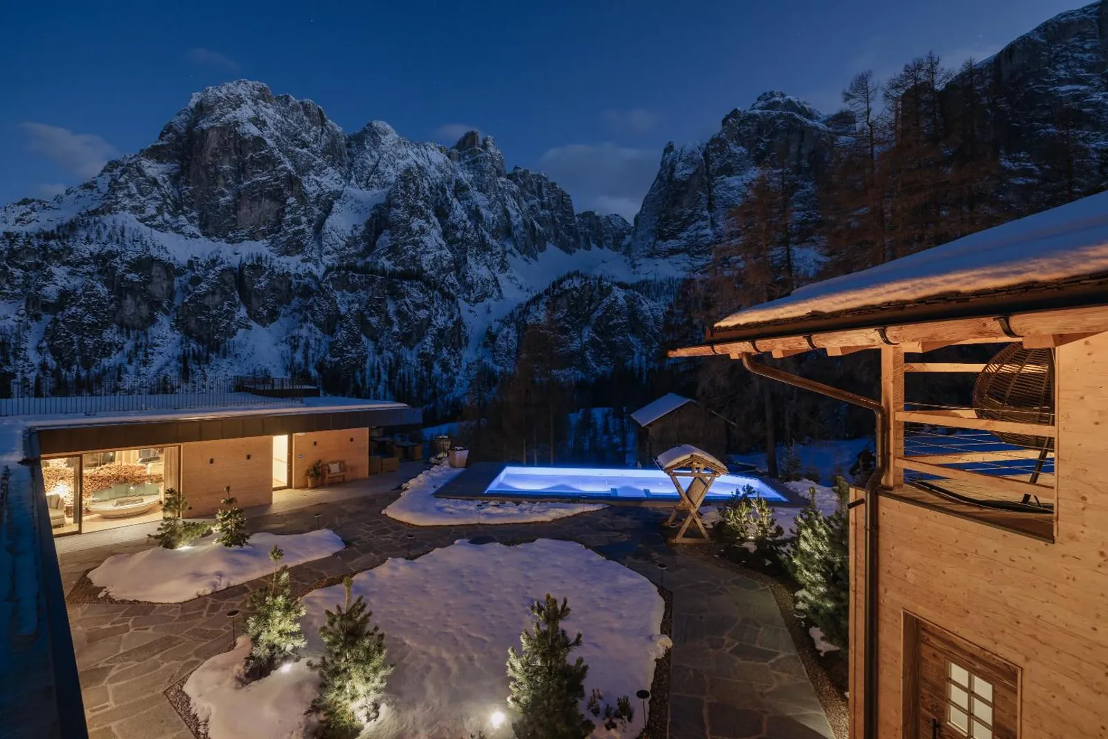Kolfuschgerhof at dusk with a lit pool and snowy peaks