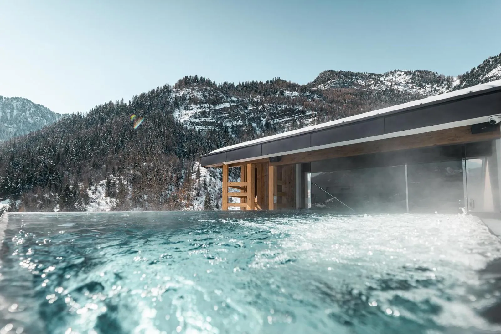 Outdoor pool steaming in winter with snowy mountains behind