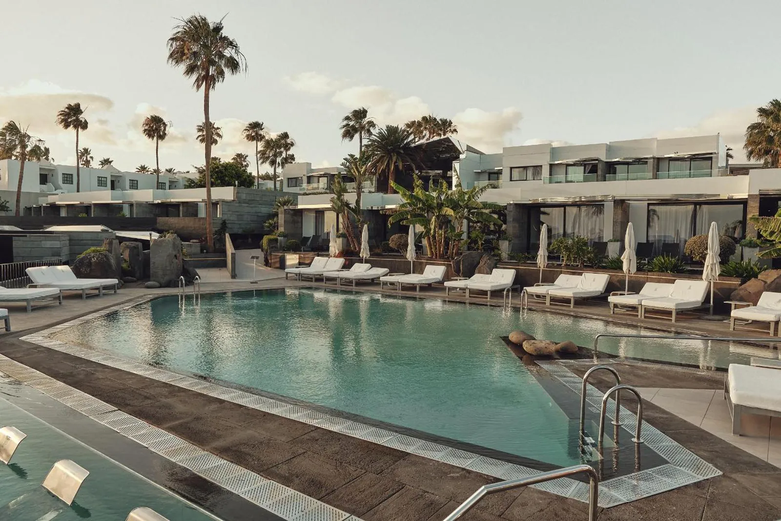Pool terrace in late afternoon light, loungers lined up along the edge