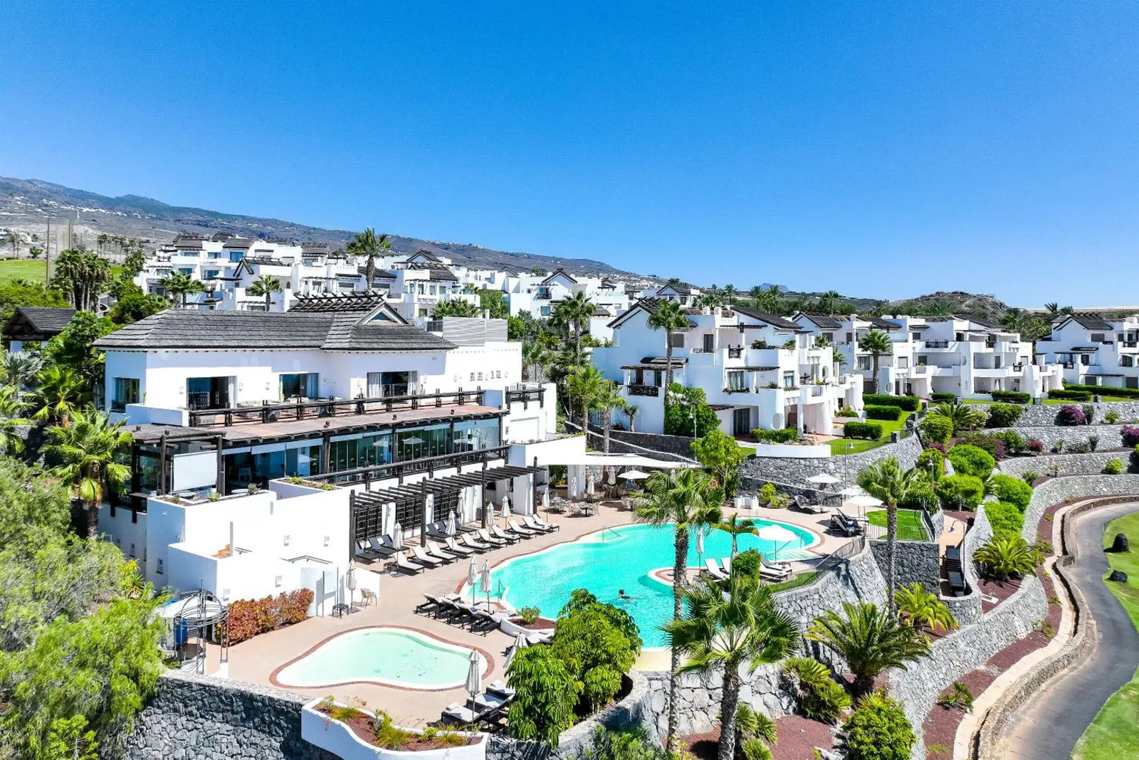 White Andalusian-style suite buildings stepped above a pool and a smaller kids' pool