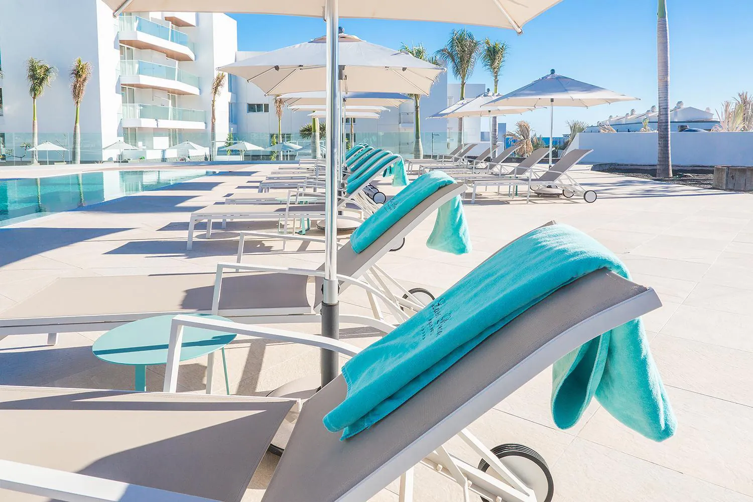 White loungers with turquoise towels lined up along the pool