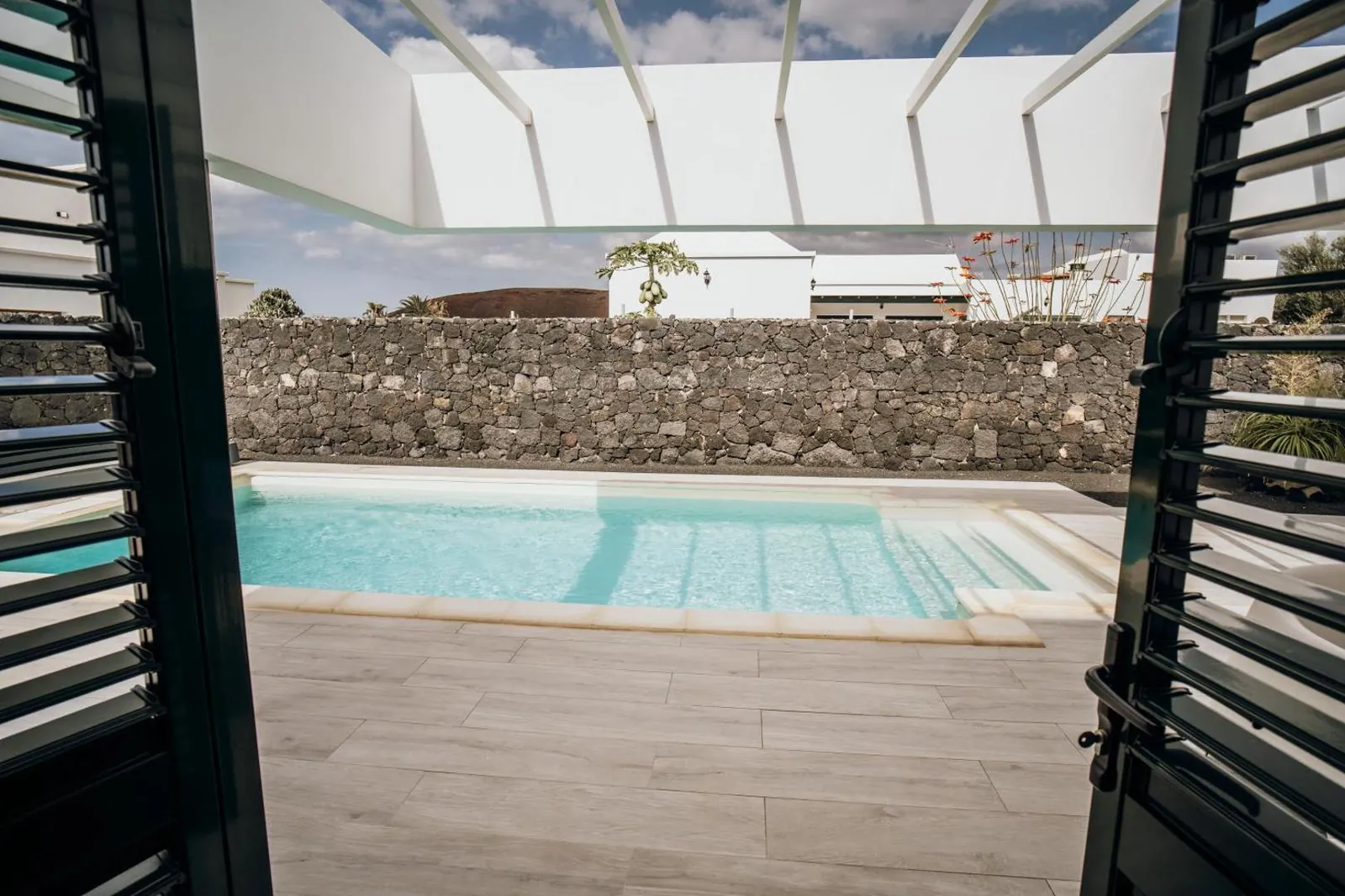 The private pool seen through open shutters from inside the villa