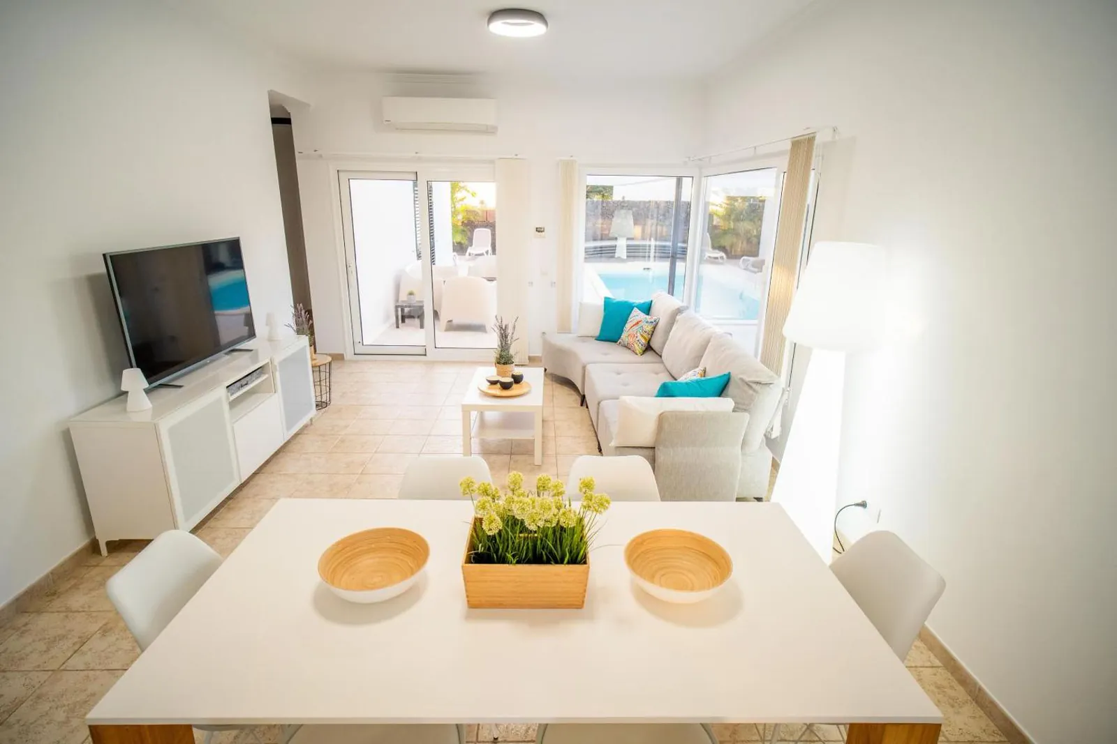 Open-plan dining and living area with a glimpse of the pool through the window
