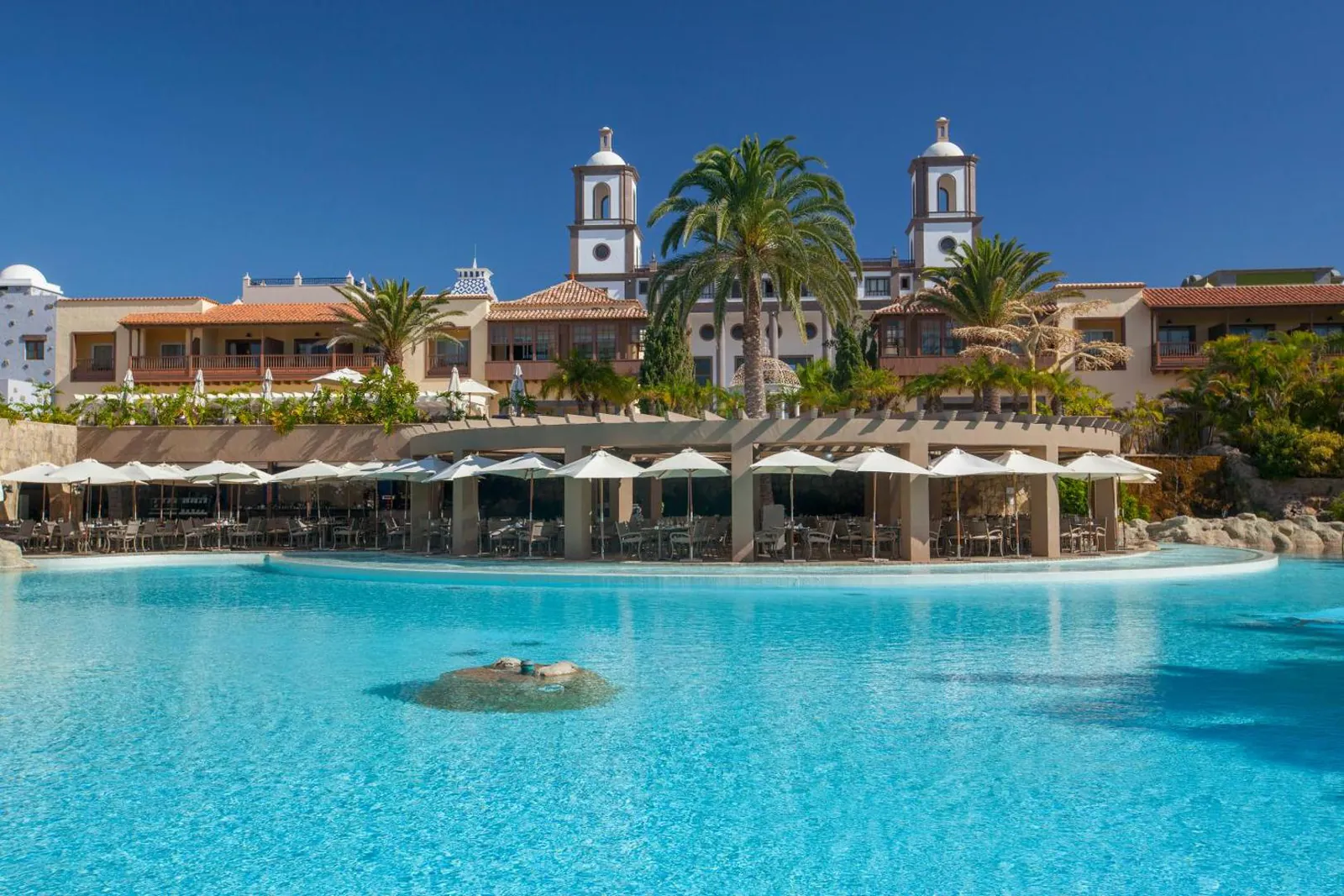 Wide lagoon-style pool in front of the Canarian-village buildings