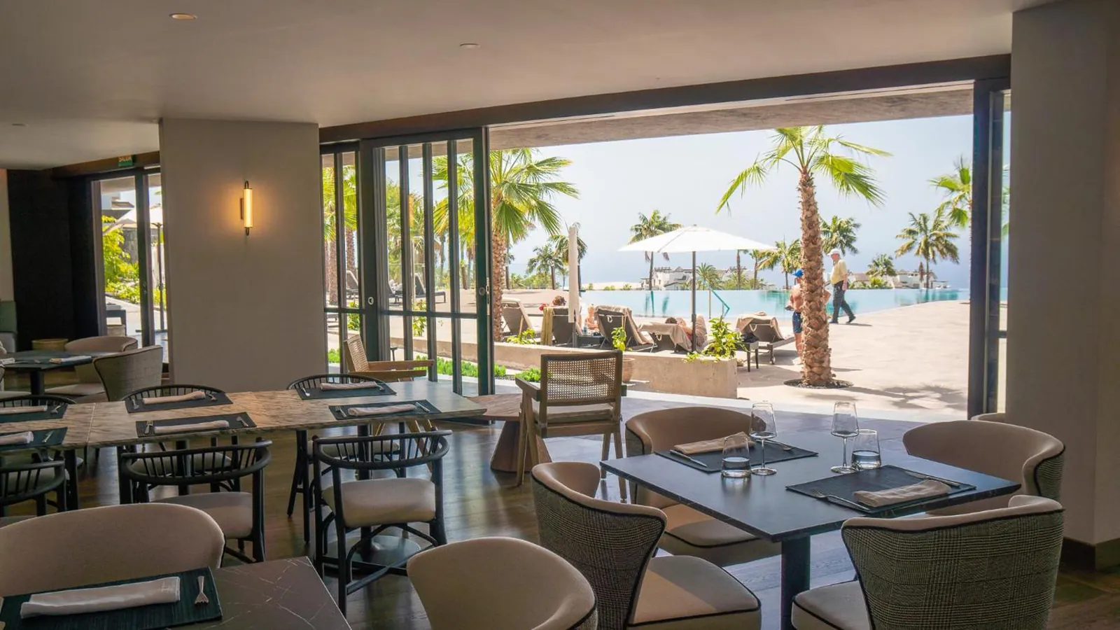 Restaurant terrace opening onto the pool and palms