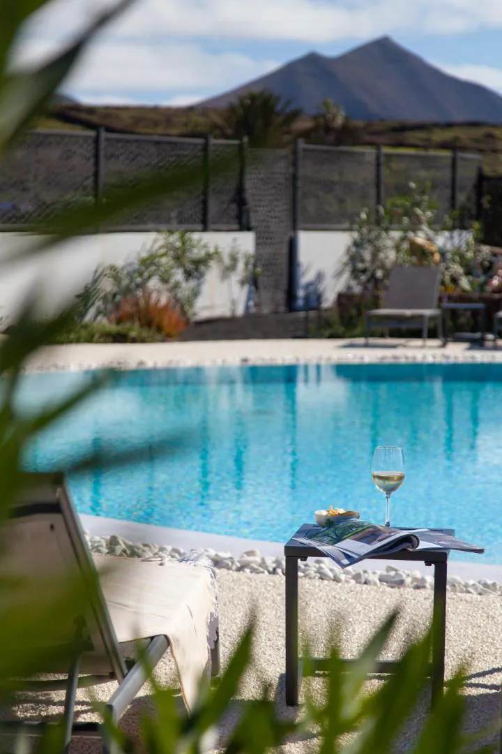 Turquoise pool water with a volcanic cone rising beyond the garden
