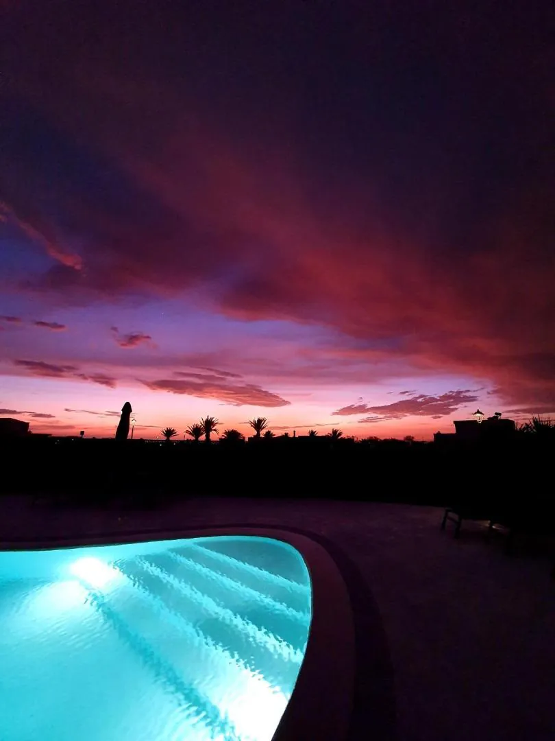 The pool lit up at dusk under a pink and purple sky