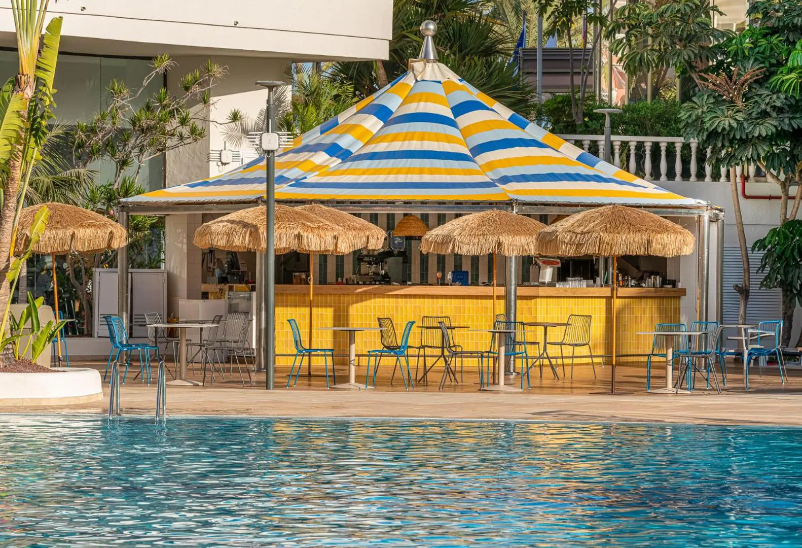 Pool bar under striped umbrellas right at the water's edge