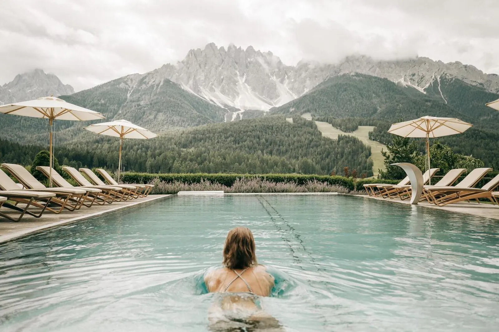 Swimmer in the heated outdoor pool at Naturhotel Leitlhof, with the Baranci peaks behind