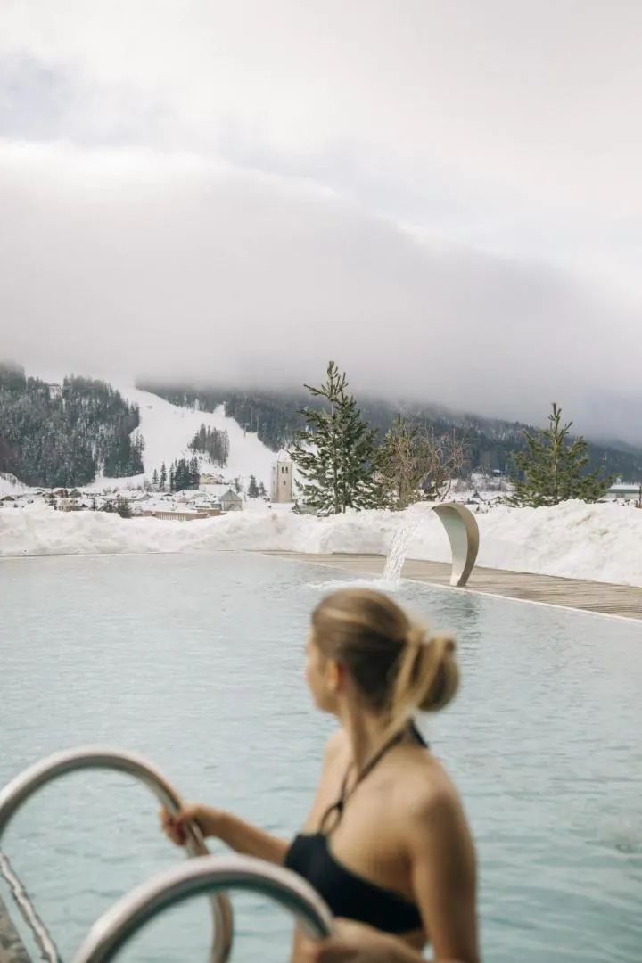Guest climbing out of the outdoor pool in winter at Naturhotel Leitlhof
