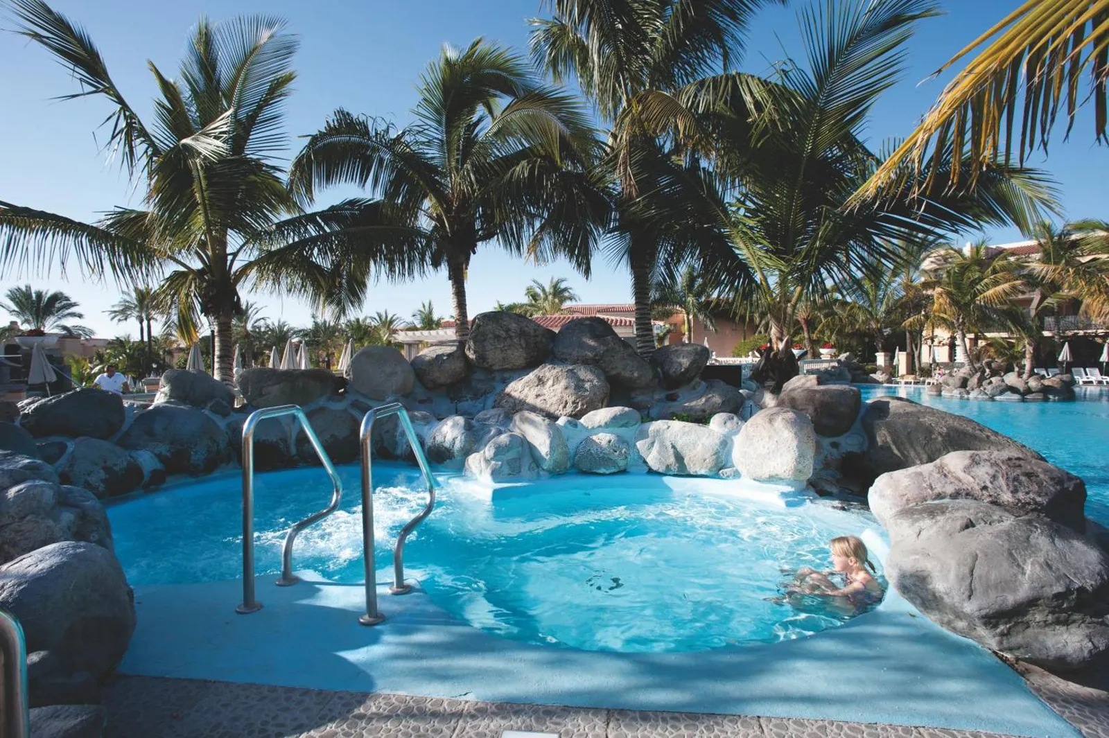 Hot tub set among volcanic rocks at the edge of the pool