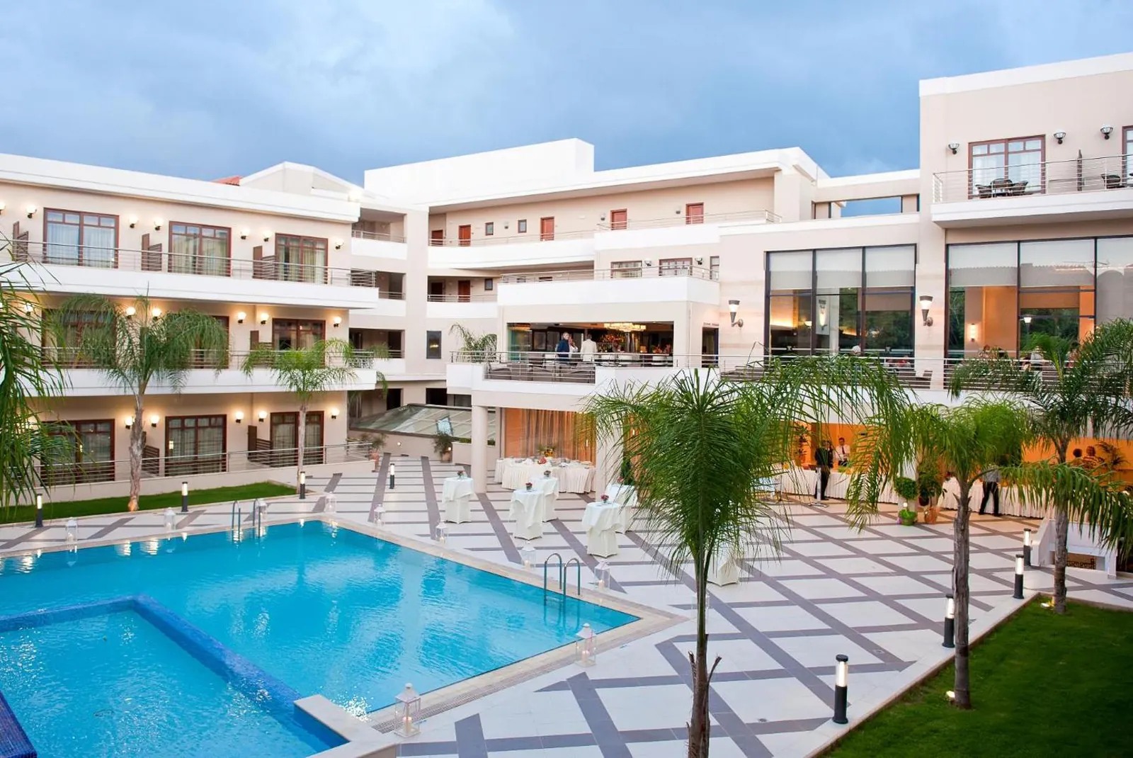 Courtyard pool surrounded by palms and the resort's white buildings