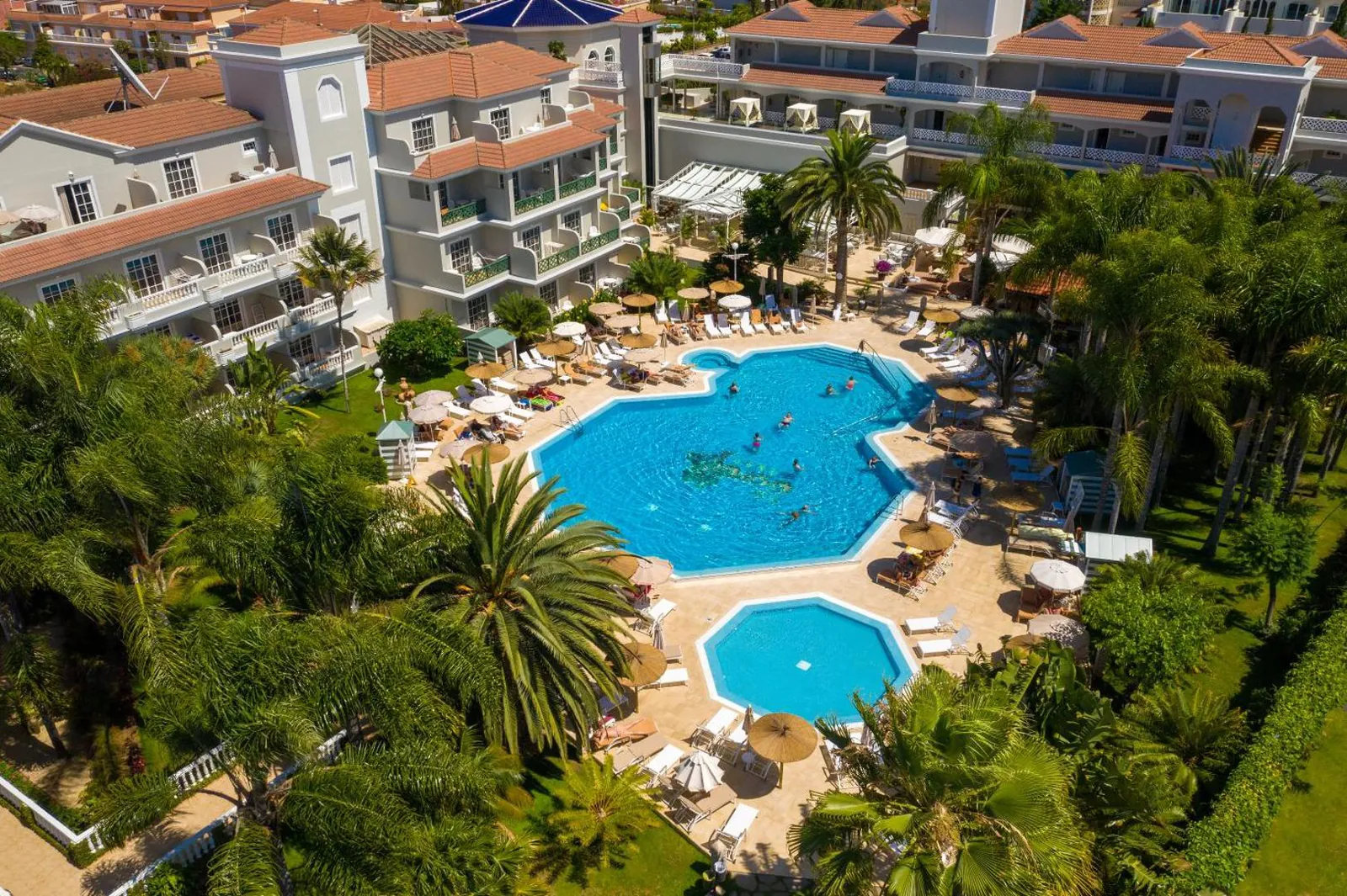 Main pool and the smaller kids' pool set in tropical gardens