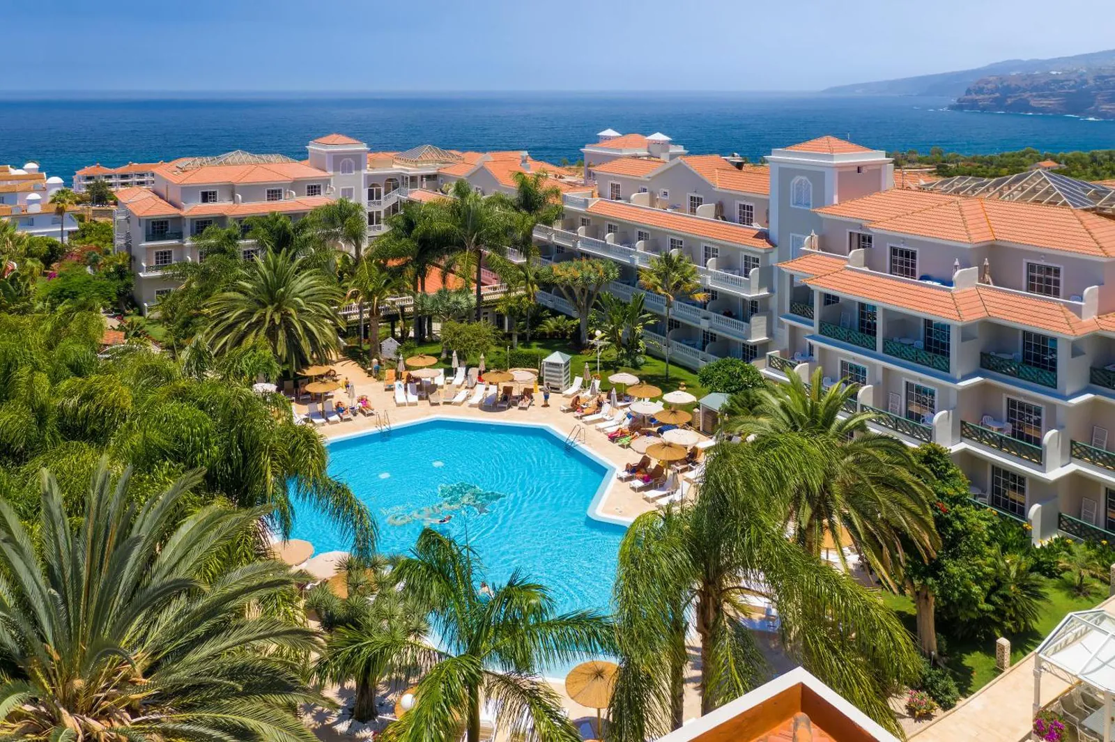 Hotel gardens and pool from above, with the coast and sea beyond
