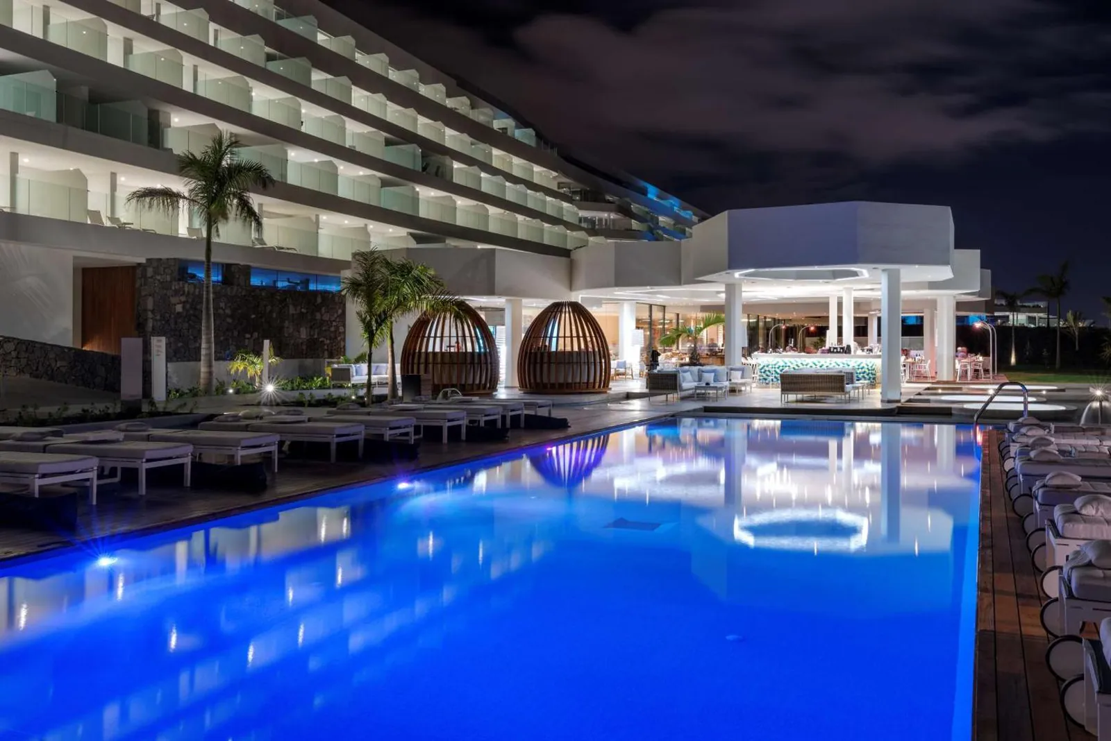 Pool lit at night beside the hotel terraces